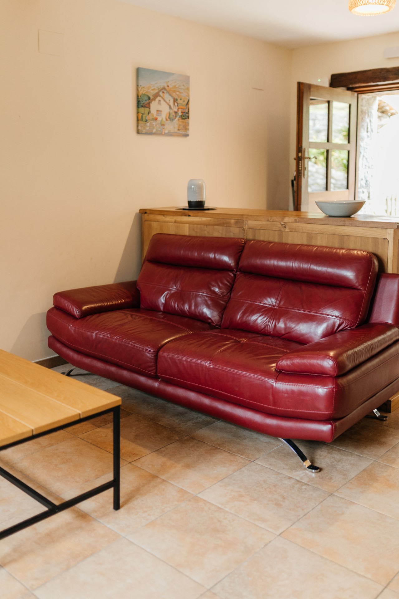 Zona-de-estar-con-sofa-rojo-de-piel-en-alojamiento-rural-acogedor-en-Asturias