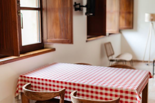 Mesa-de-comedor-con-mantel-de-cuadros-rojos-en-cocina-de-casa-rural-en-Llanes