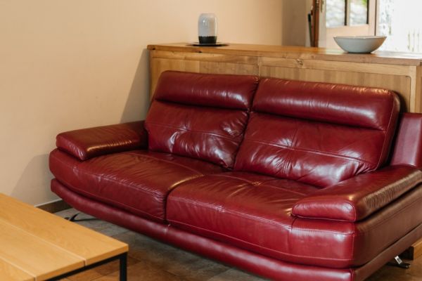 Zona-de-estar-con-sofa-rojo-de-piel-en-alojamiento-rural-acogedor-en-Asturias